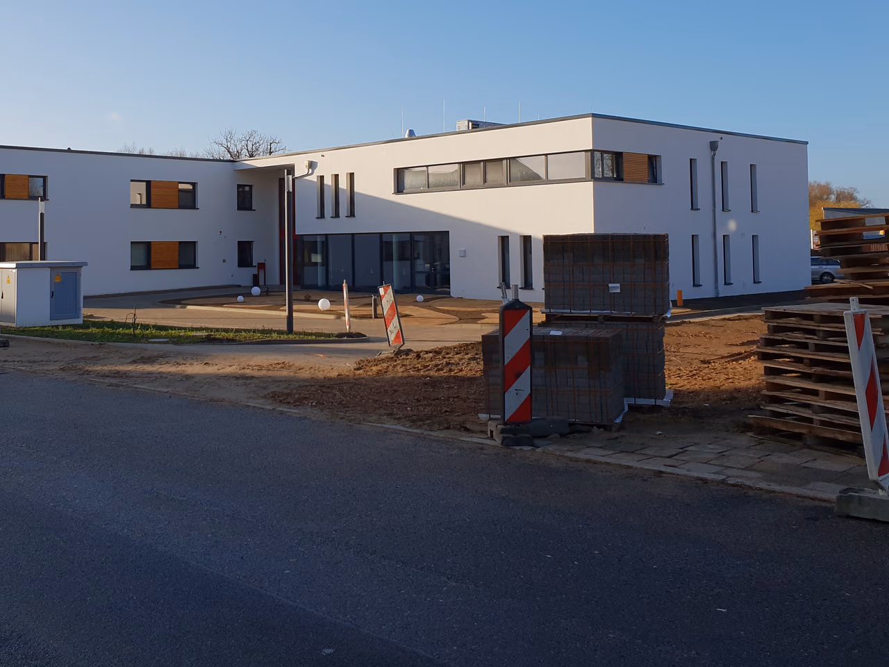 Pflegeheim von der Straße aus: weißer Flachdachbau mit Fensterbändern und Holzelementen
